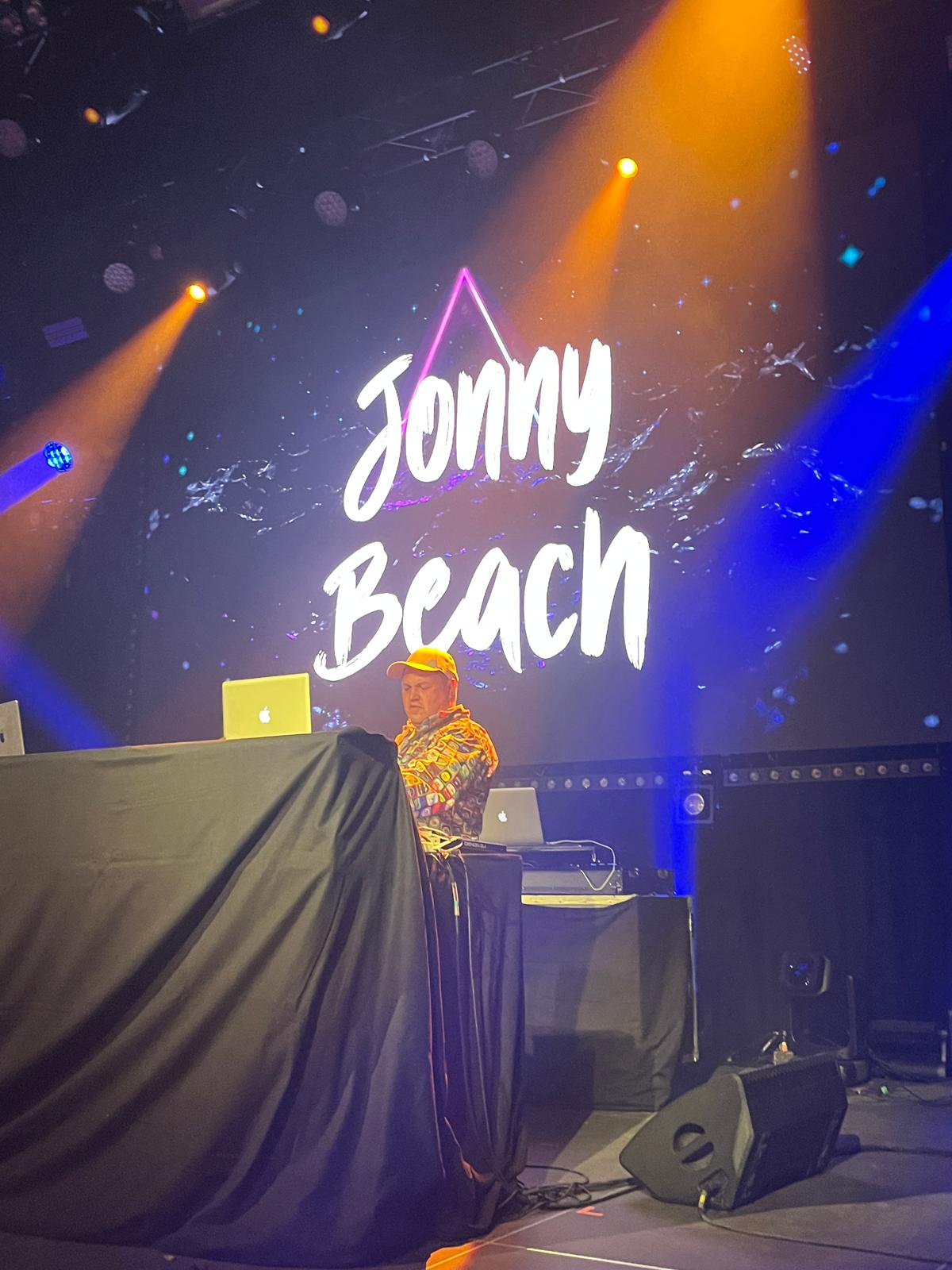Jonny Beach am DJ-Pult auf der Bühne unter Bühnenlicht